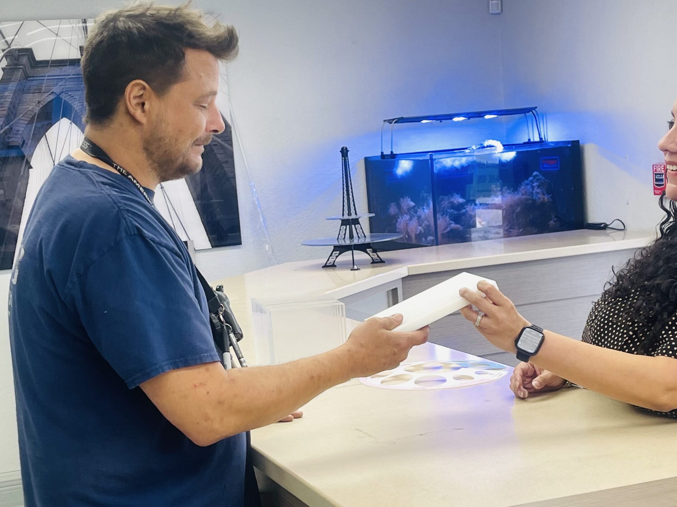 Customer service representative assisting a client at the counter with custom plastic fabrication services.